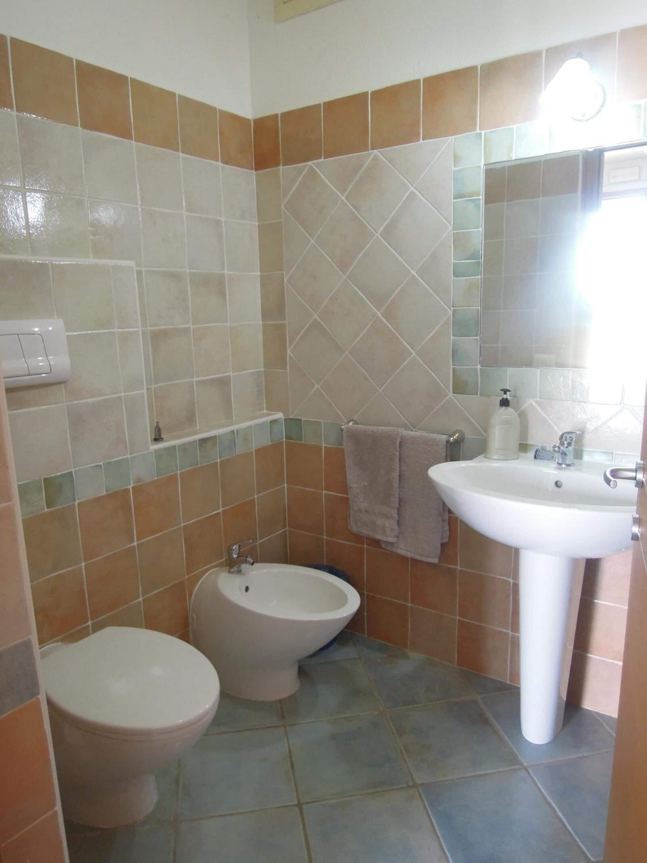 Casa de banho com sanita, bidé e lavatório.