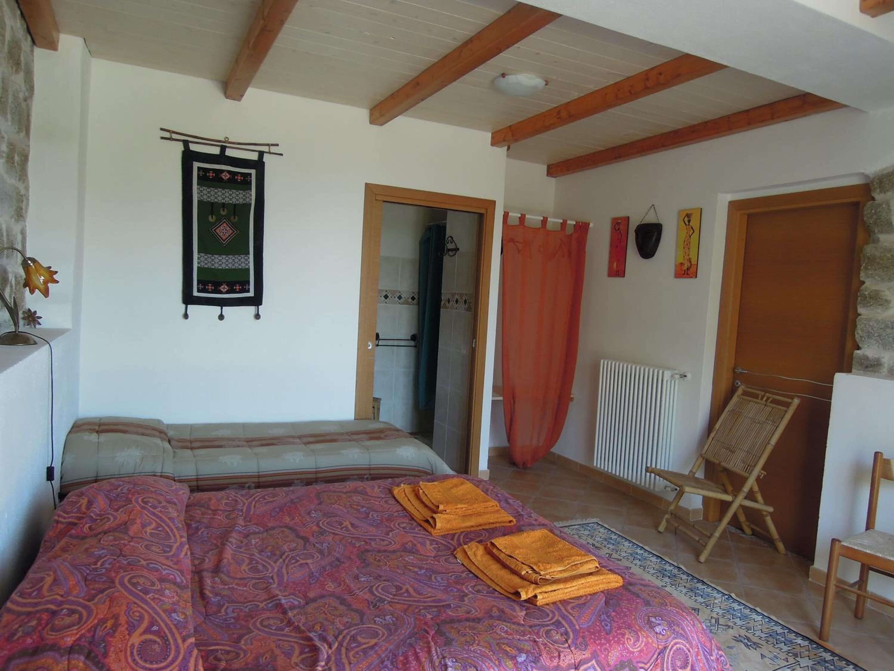 Ein Schlafzimmer mit einem Bett, Holzboden, Heizkörper und einem Sessel.