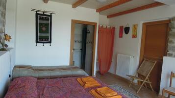Ein Schlafzimmer mit einem Bett, Holzboden, Heizkörper und einem Sessel.