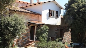 Una casa de dos pisos con fachada de piedra, techo de tejas y un pequeño porche delantero.