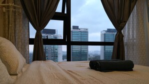 Una habitación de hotel con una cama grande, vistas a edificios altos y una ventana con cortinas.