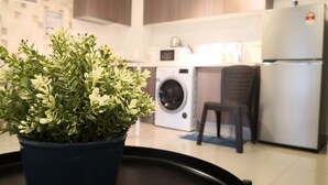 Una cocina moderna con lavadora, refrigerador y una planta en maceta.