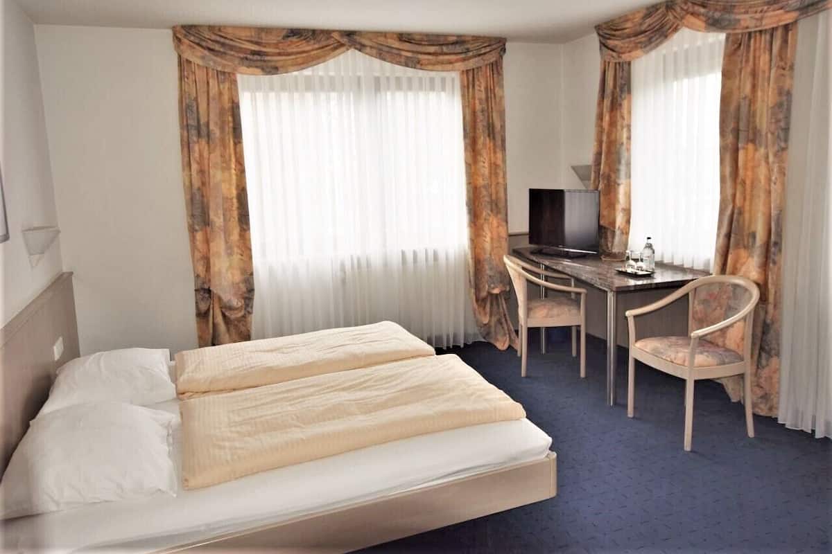 Ett hotellrum med en säng, ett skrivbord och en stol.