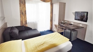 A hotel room with a bed, a desk, a chair, a television, and a wardrobe. - Hotel Alena (Filderstadt)