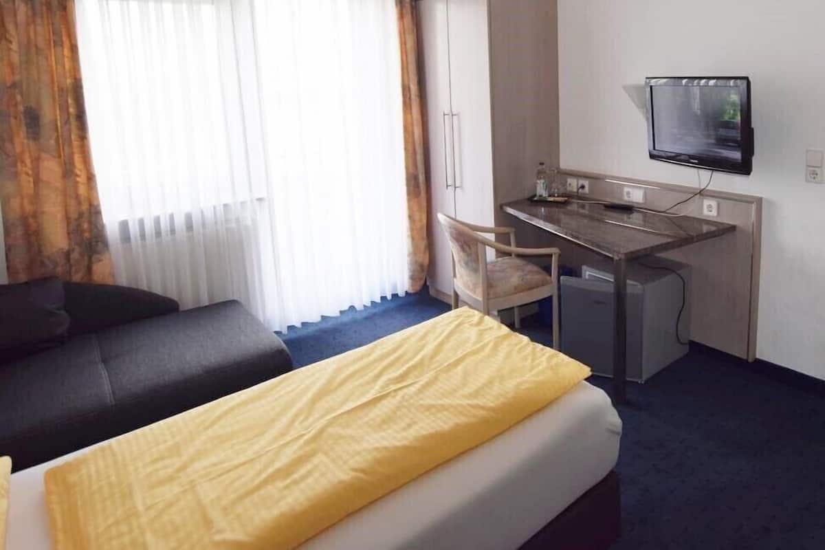 Ett hotellrum med en säng, ett skrivbord, en stol, en tv och en garderob.