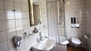 A bathroom with a sink, mirror, towel rack, toilet, and shower. - Hotel Alena (Filderstadt)