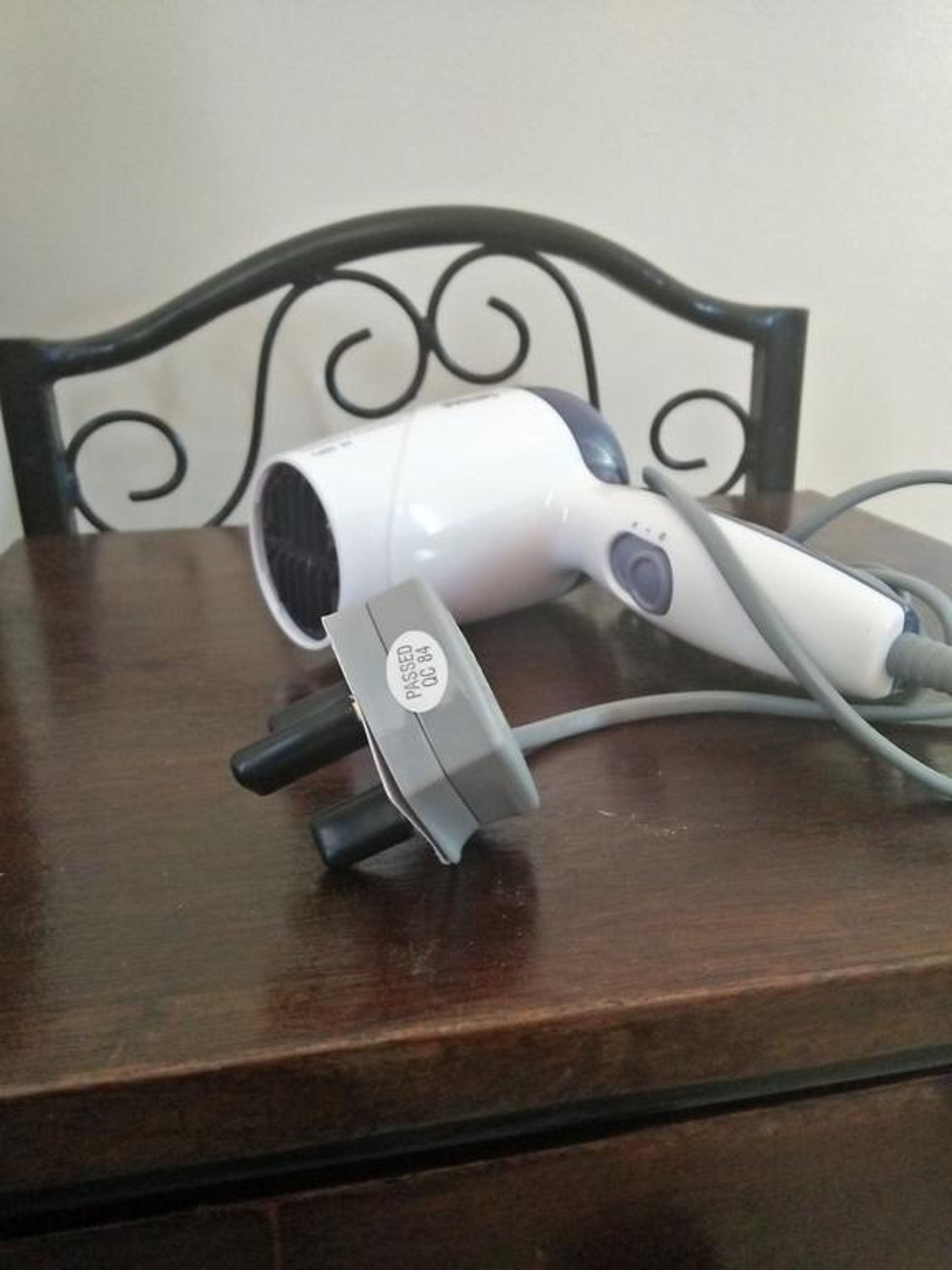 A hair dryer on a wooden table with a metal headrest.
