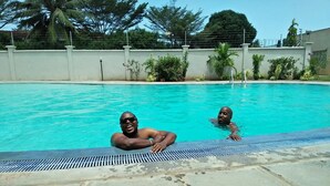 A swimming pool with two people in the water. - Barizi Holiday Apartments (Mtwapa)