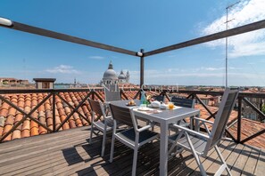 Eine Terrasse mit Tisch und Stühlen mit Blick auf eine Stadtlandschaft mit Kuppelbauten.