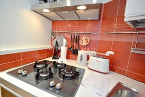 A kitchen with a gas stove, a toaster, and a kettle.