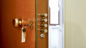 Uma porta com maçaneta de latão, um olho de fechadura e um chaveiro com etiqueta.