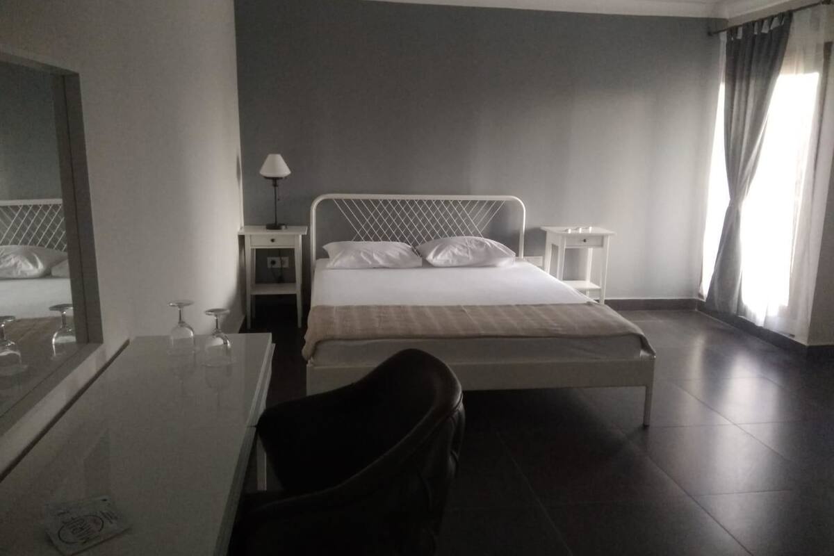 A hotel room with a bed, bedside tables, a desk, and a chair.