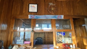 Un intérieur en bois avec un comptoir en pierre, une enseigne encadrée et un gouvernail de bateau.