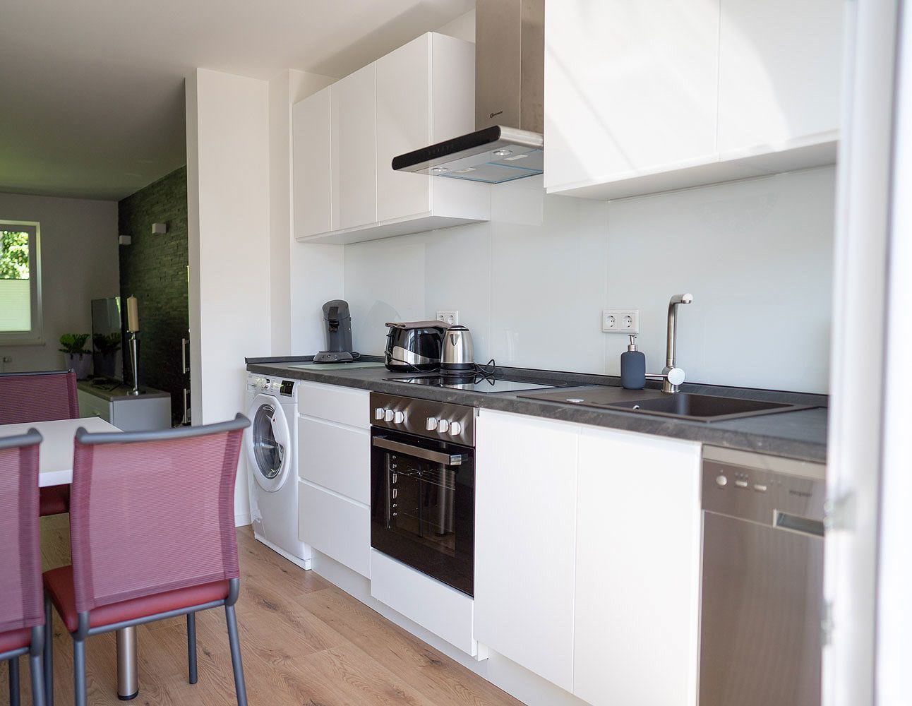 A modern kitchen with white cabinets, a stainless steel oven, and a dishwasher.