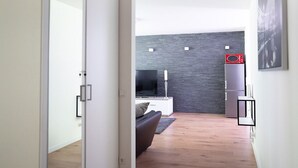 Un salon moderne avec un téléviseur à écran plat, un canapé gris et un mur en briques sombres.