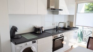 Une cuisine compacte équipée d’un lave-linge, d’une machine à café, d’une bouilloire et d’une cuisinière.
