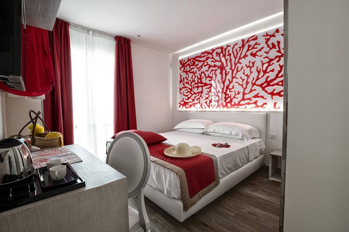 Une chambre d’hôtel moderne équipée d’un lit, d’un bureau avec une bouilloire et des tasses, ainsi que d’un panneau décoratif mural.