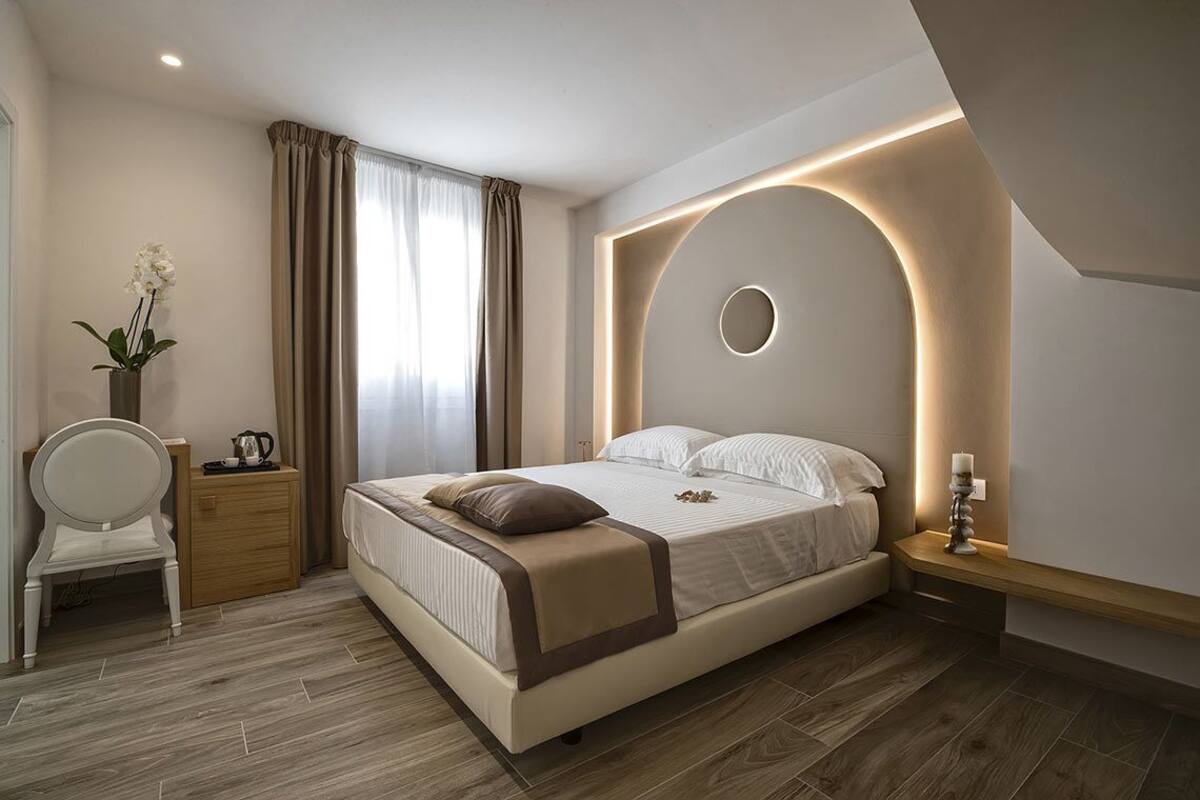 Une chambre à coucher moderne avec un lit, une table de chevet, une chaise et un vase de fleurs.