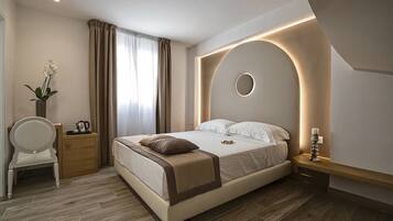 A modern bedroom with a bed, bedside table, chair, and a vase with flowers.