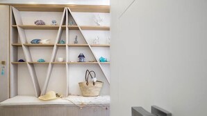 Une pièce moderne dotée d’une banquette intégrée, d’étagères ornées d’objets décoratifs et d’un panier contenant un chapeau.
