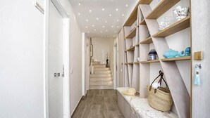 Un couloir doté d’un plancher en bois, d’un banc avec un panier, et d’étagères ornées d’objets décoratifs.