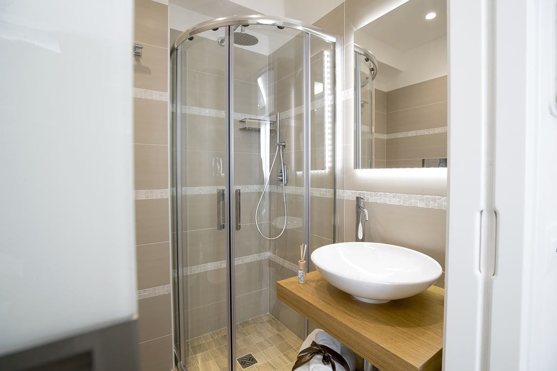 Een moderne badkamer met een douchecabine van glas, een wit wastafelmeubel en een houten opbergkast.