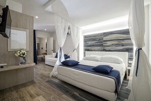 Une chambre à coucher moderne avec un grand lit, une coiffeuse avec un miroir et un téléviseur fixé au mur.