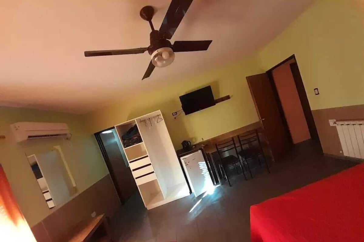 Una habitación con ventilador de techo, una cama, un escritorio y una silla.