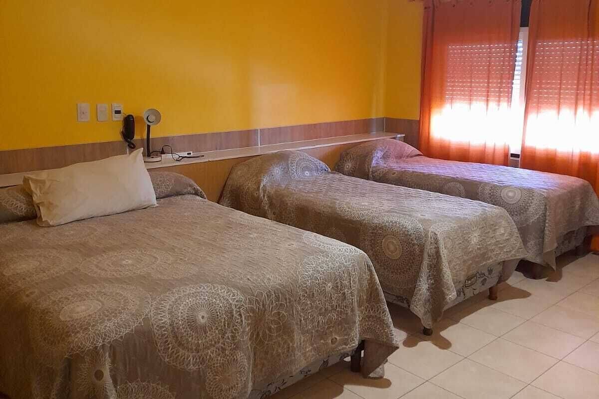 Habitación de hotel con dos camas, un ventilador de techo y una ventana con cortinas.