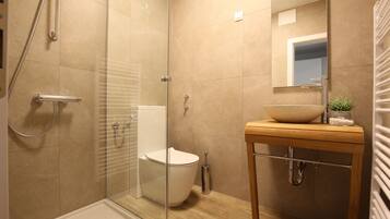 Une salle de bain moderne avec une douche à parois de verre, des toilettes blanches et un meuble-lavabo en bois avec un vasque intégrée.