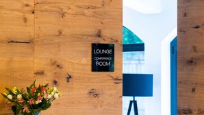 A wooden wall with a sign reading "Lounge Conference Room" and a table with a bowl of fruit and a vase of flowers. - Hotel Ortus Residence (Ankaran)