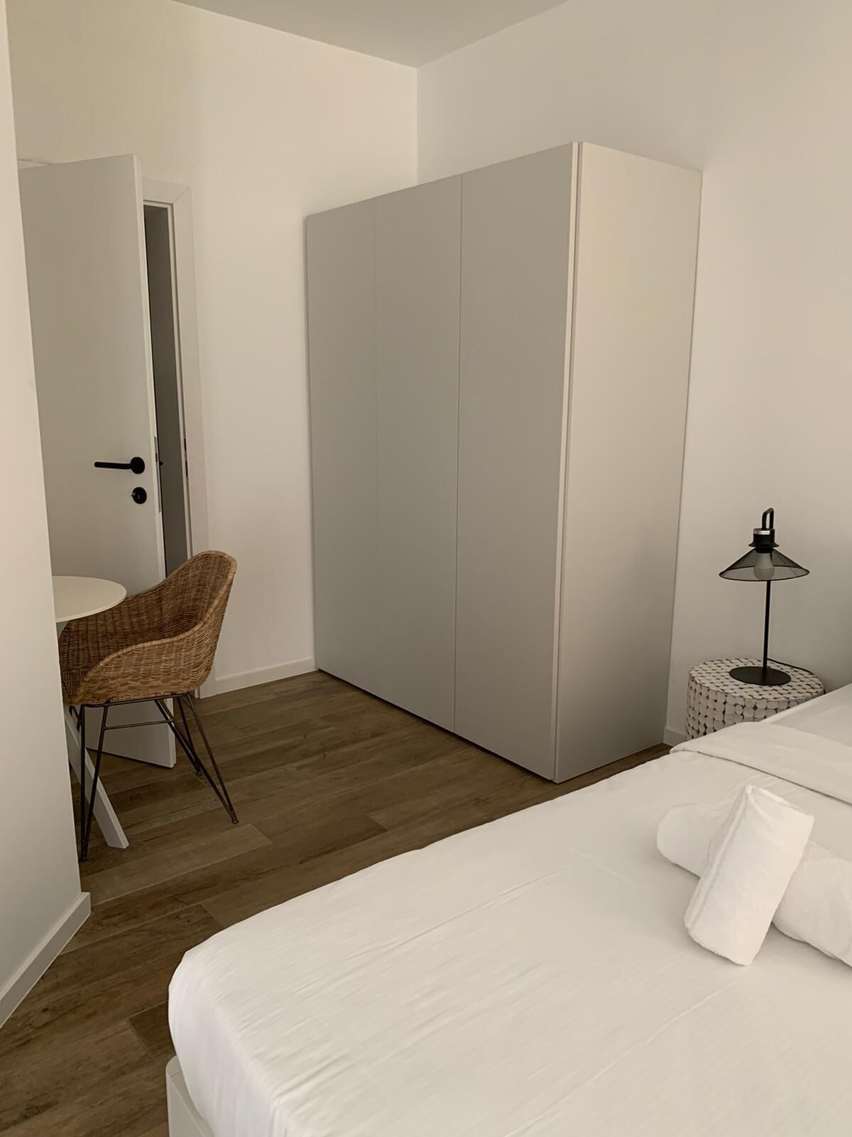 Ein Schlafzimmer mit einem Bett, einem Sessel, einem Kleiderschrank und einem Nachttisch mit einer Lampe.