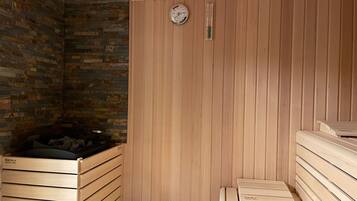 A sauna room with wooden benches and a stone wall.