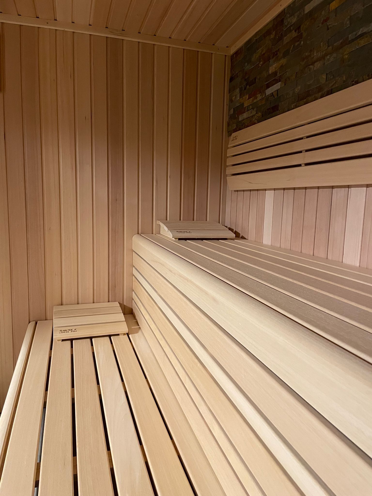 Un sauna avec des bancs en bois et un plancher incliné.