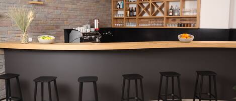 Eine Bar mit einer Holztresen, schwarzen Barhocker und einer Ziegelwand.
