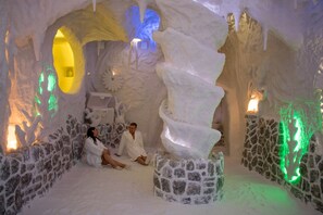 Una cueva de hielo con una escultura central de hielo, paredes de piedra e iluminación ambiental.