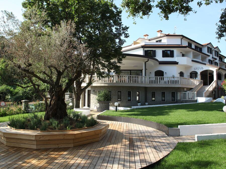 A large, multi-story building with a white exterior and a balcony.