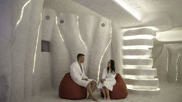 Um casal sentado em sacos de feijão em um quarto com um design de parede texturizado e uma luminária em formato de escada.