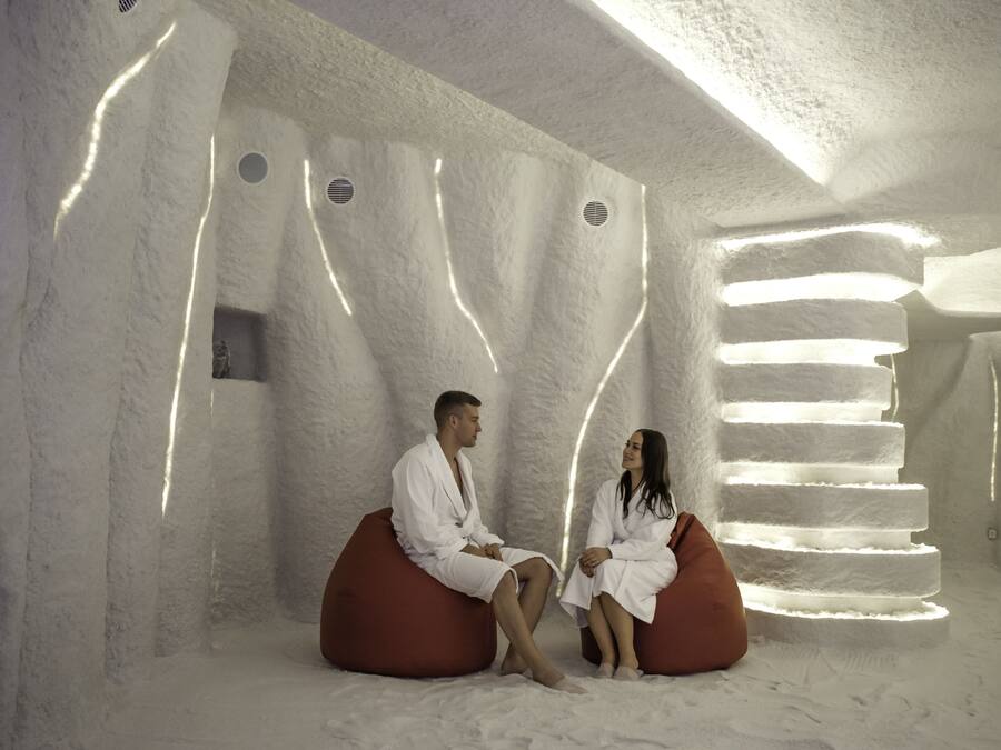 A couple sitting on bean bags in a room with a unique, textured wall design and a staircase-like light feature.