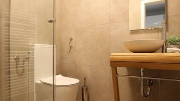 A modern bathroom with a glass-enclosed shower, a freestanding bathtub, and a wooden vanity with a bowl sink.