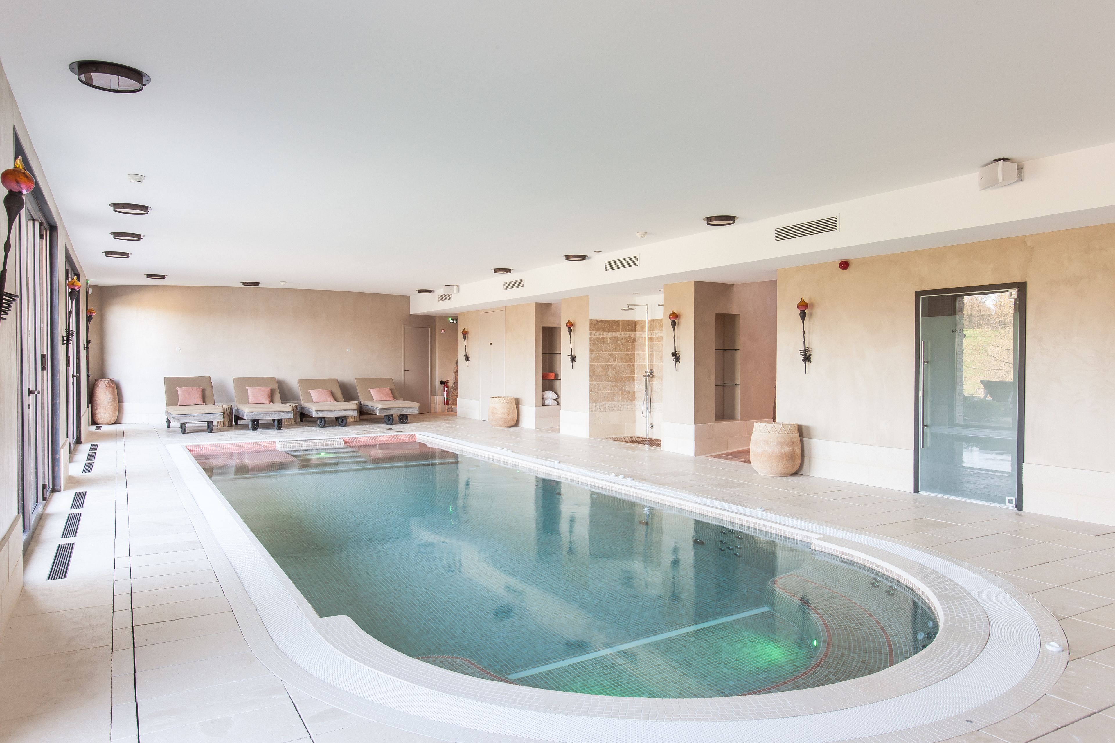 A large indoor swimming pool with lounge chairs and a spa area.