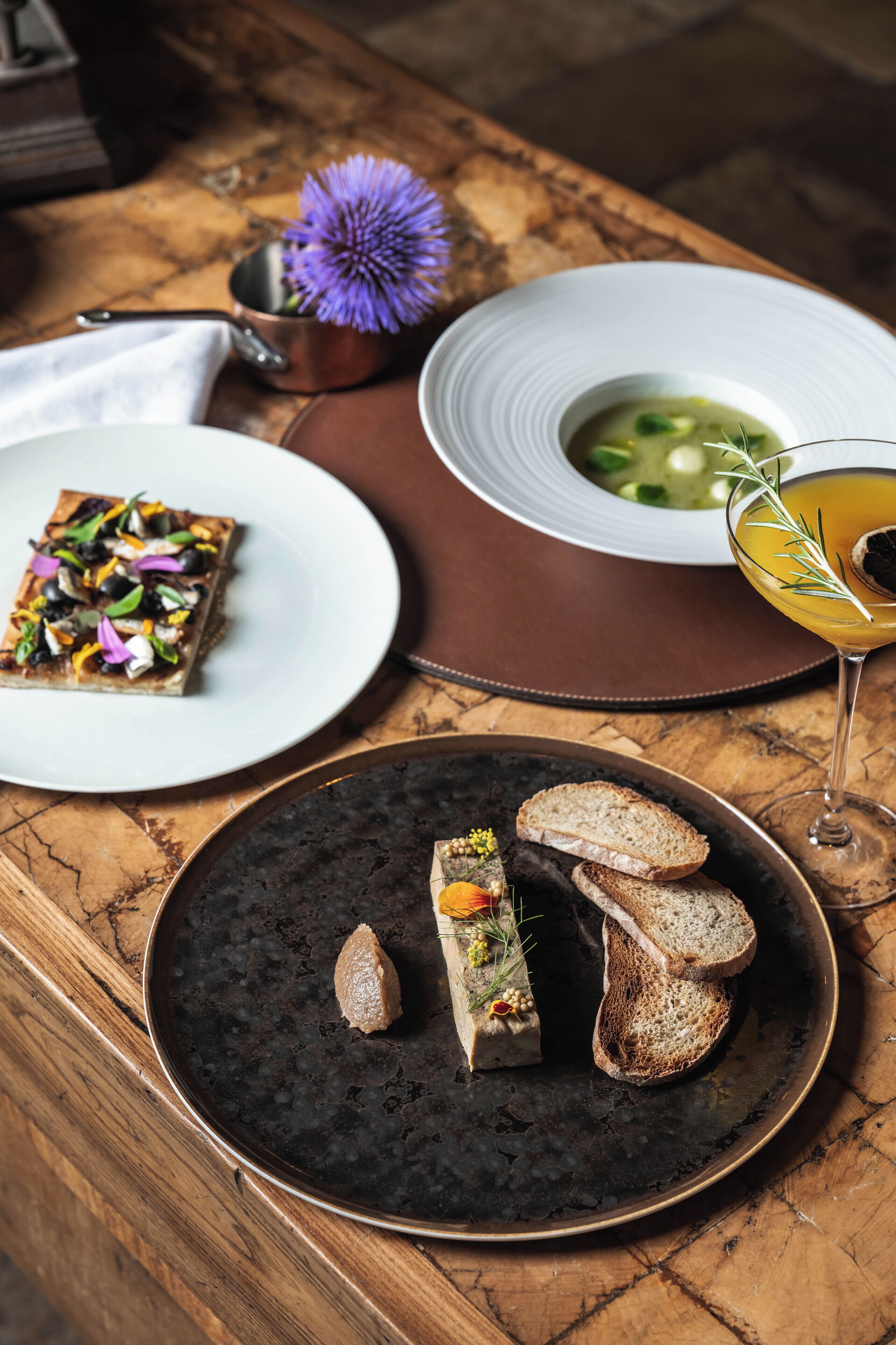 A table with a variety of dishes including a soup, a salad, and a dessert.
