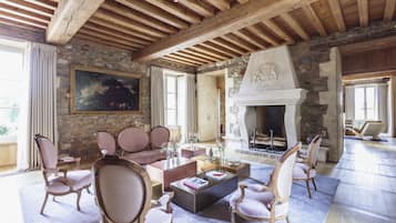 A spacious living room with a stone fireplace, wooden beams, and comfortable seating.