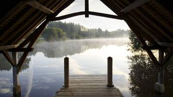 A wooden pier leading to a calm lake with a forested background.