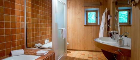 A bathroom with a wooden interior, a bathtub, a sink, and two windows.