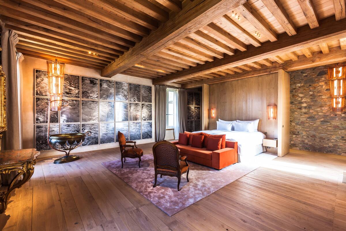 Une pièce spacieuse avec un grand lit, un plafond en bois et un mur en pierre.