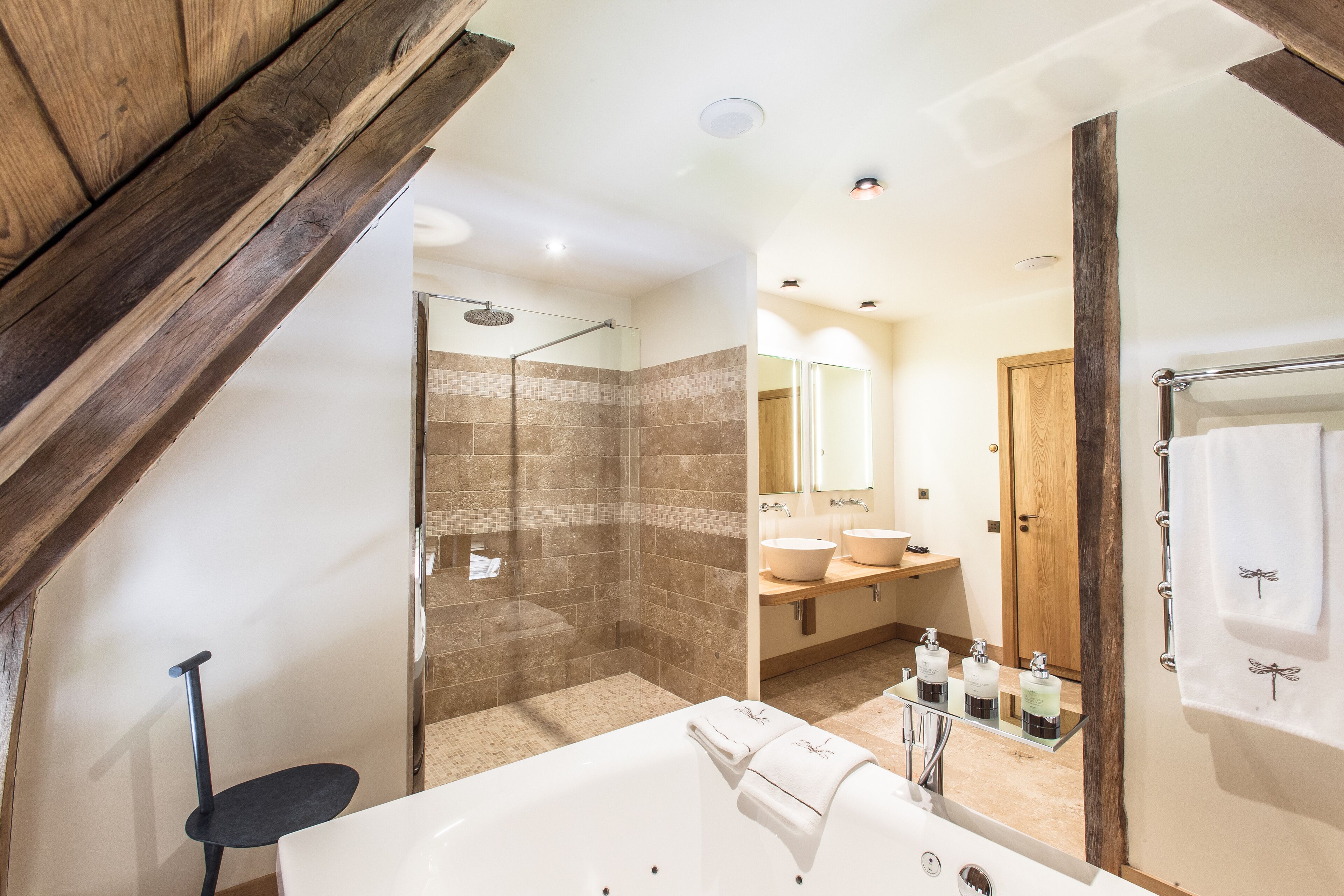 A modern bathroom with a bathtub, a shower, and a vanity with two sinks.