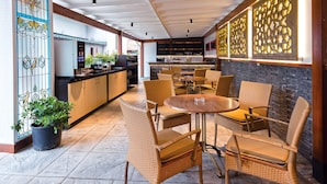 A modern outdoor seating area with wicker chairs and a round table, a kitchen area with a grill, and decorative glass panels. - Princess Residence (Istanbul)