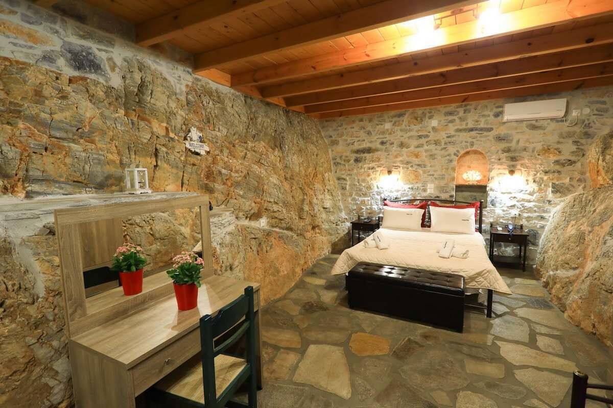 Een kamer met stenen muren, een bed, een houten bureau en een stoel.