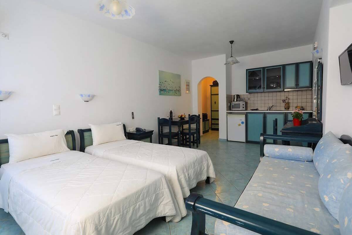 Een compacte hotelkamer met twee bedden, een kitchenette en een eethoek.